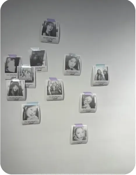 회색 벽에 삼각형 모양으로 붙인 다수의 인물 영수증사진(ANAP 브랜드 태그)